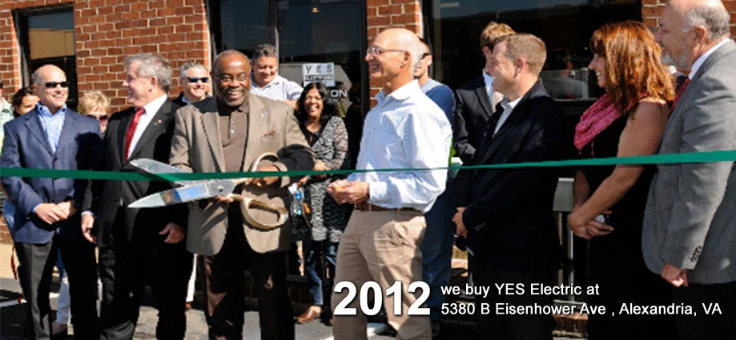 Nuestra historia 7 A group of people is gathered outside a building for a ribbon-cutting ceremony, with a man holding large scissors. Text reads: "2012 we buy YES Electric, an Electrical Distribution Company, at 5380 B Eisenhower Ave, Alexandria, VA.