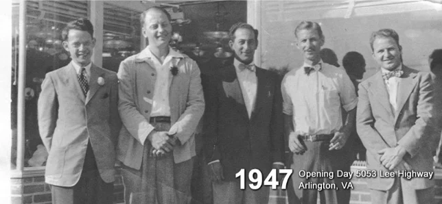 Nuestra historia 2 Five men in suits and bow ties stand in front of a building, marking the 1947 Opening Day of an Electrical Distribution Company. Text reads: "1947 Opening Day 5053 Lee Highway Arlington, VA.